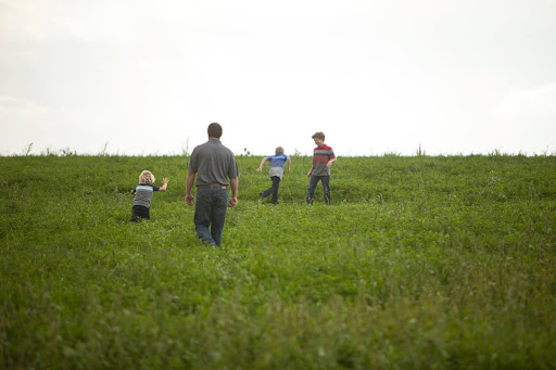 A-dairy-farmer-and-his-children-running-together-through-a-grassy-field-on-a-dairy-farm.jpg A dairy farmer and his children running together through a grassy field on a dairy farm.